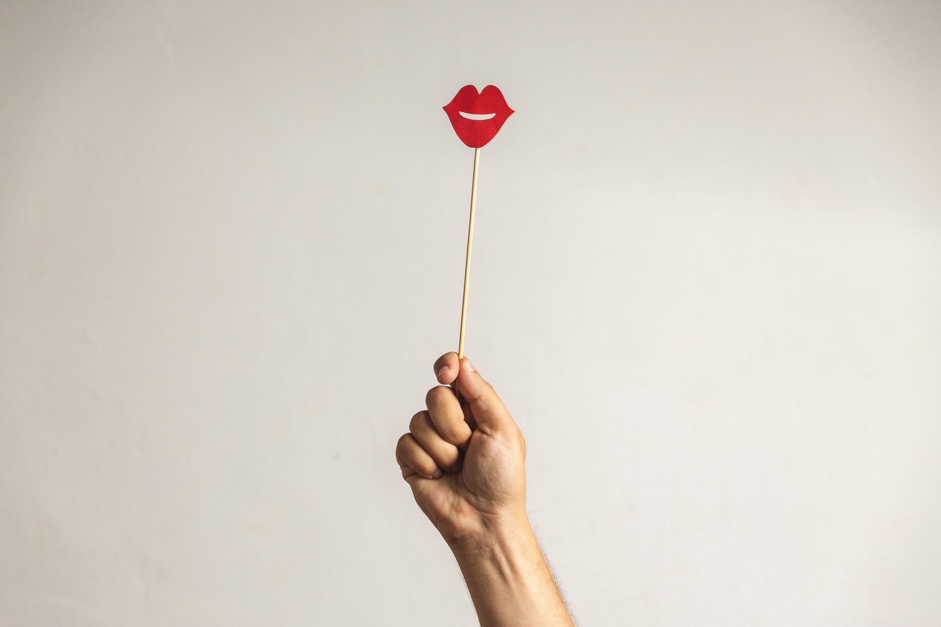 Cropped Hand Holding Lips Prop Against White Background